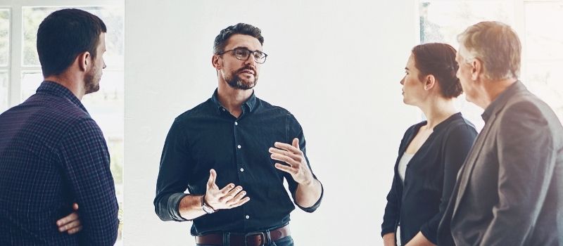 Menschengruppe steht zusammen als symbolische Darstellung eines Beratungsprozesses im Rahmen von Business Consulting, Tool-Implementierung & Projektmanagement​.