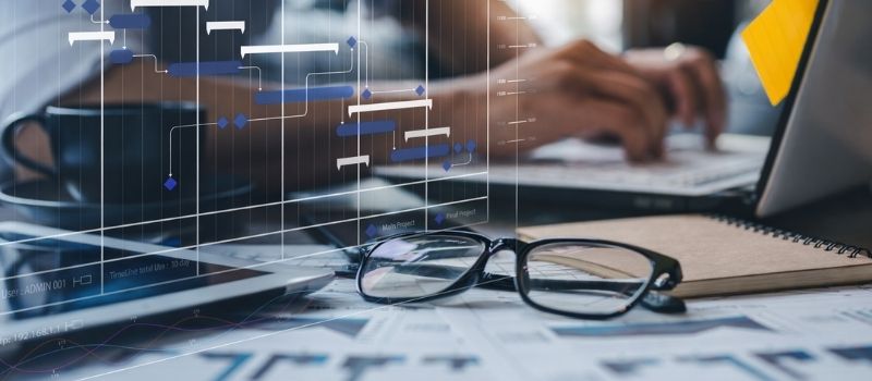 Laptop-Arbeitsplatz mit Projektplan und Zeitdiagramm als symbolische Darstellung für effizientere Prozesse und optimierte Abläufe.