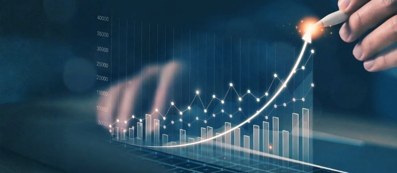 Menschliche Hand zeichnet das Diagramm einer steigenden Wachstumskurve als Symbolbild für die Steigerung von Umsatz und Profit.